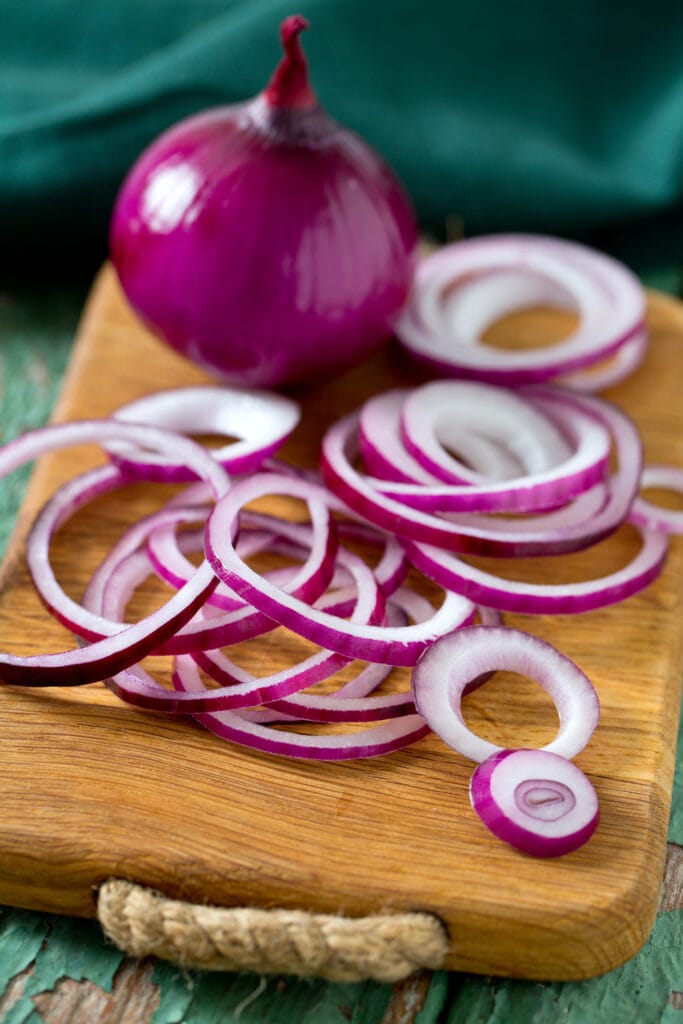 purple onions sliced on wood cutting board