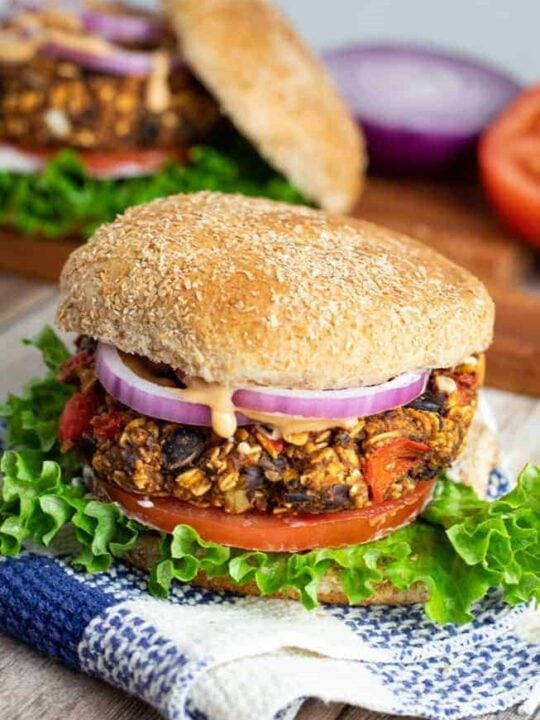 vegan black bean burger on a bun with lettuce, tomato, and onion