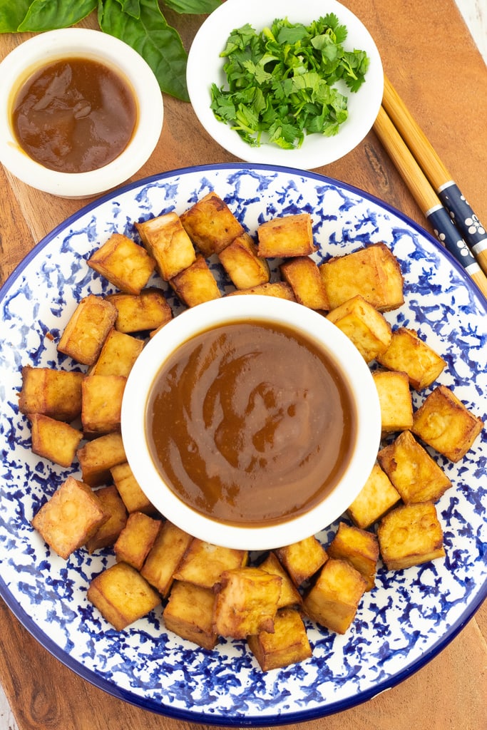 colorful blue and white plate filled with fried tofu with white bowl of sweet and sour sauce in middle