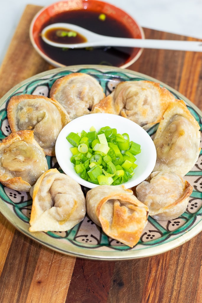 colorful plate of crispy vegan dumplings with chives and sauce