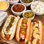 vegan hotdogs made from carrots with bowls of toppings sitting around them.