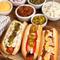 vegan hotdogs made from carrots with bowls of toppings sitting around them.