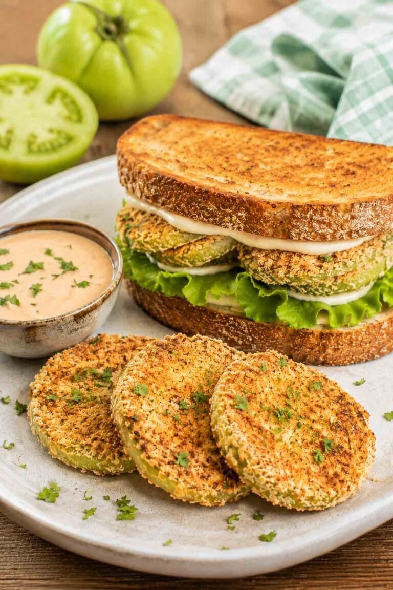fried green tomatoes on a sandwich with leafy greens and mayo.