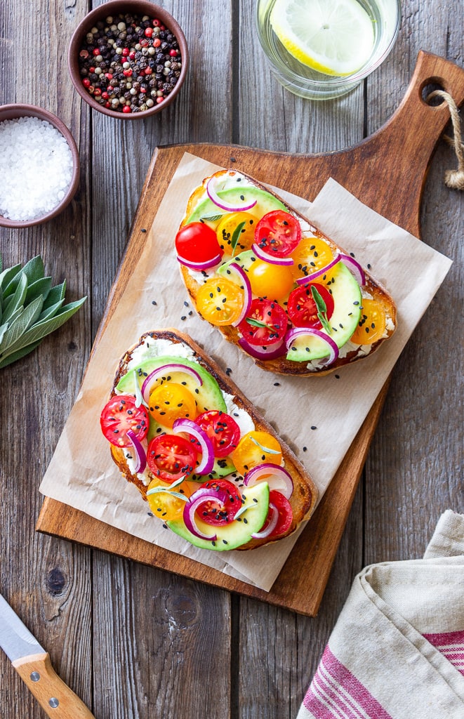 Avocado toast with tomatoes on cutting board