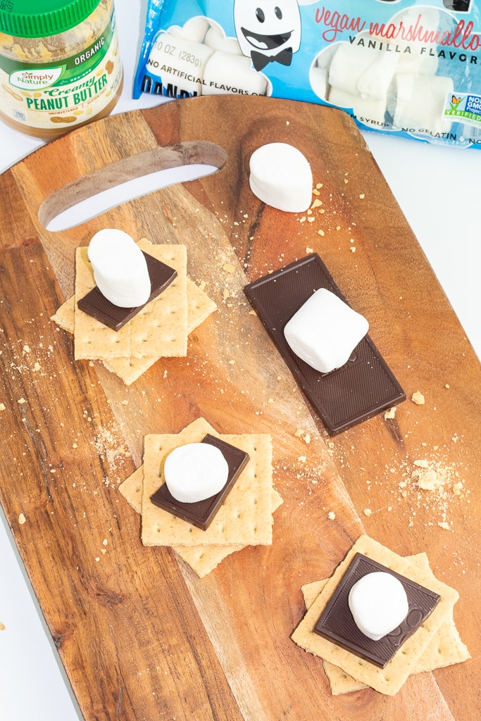overhead shot of graham crackers, chocolate, and marshmallows on wooden cutting board