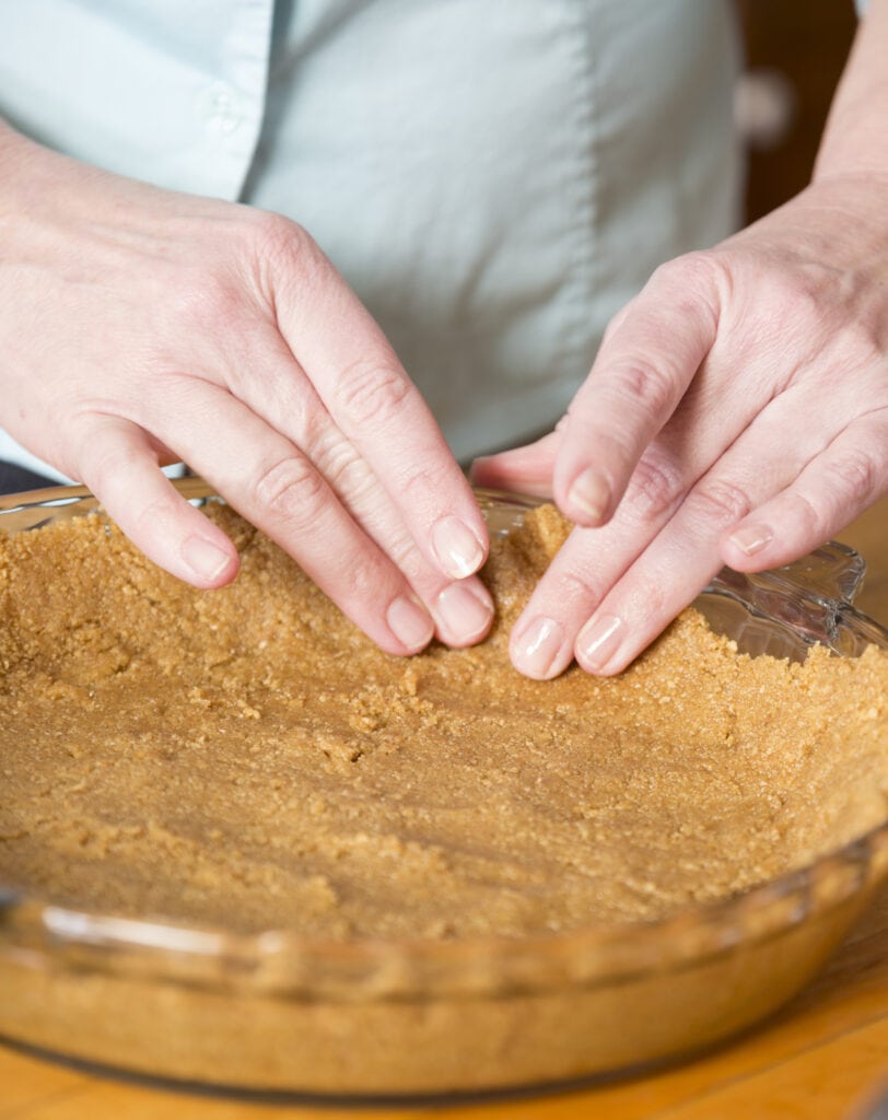 Spreading a graham cracker crust in a pie pan.
