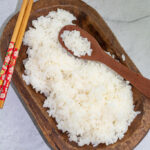 sushi rice in wooden oval shaped bowl with chopsticks