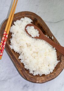 sushi rice in wooden oval shaped bowl with chopsticks
