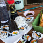 sweet potato sushi roll slices on plate and wooden table with soy sauce in background