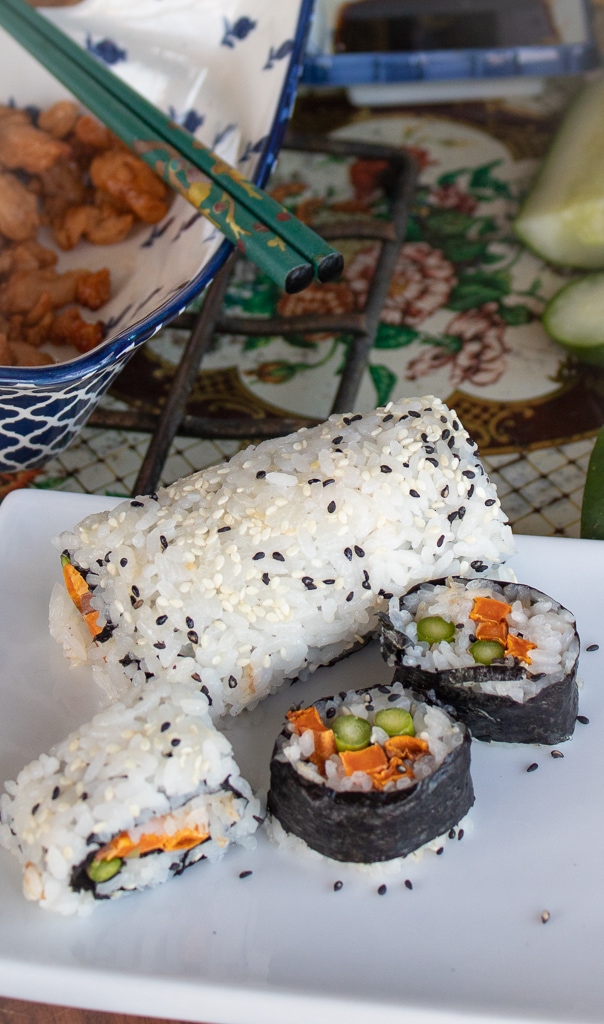 sweet potato vegetable sushi rolls and slices on white plate with chopsticks