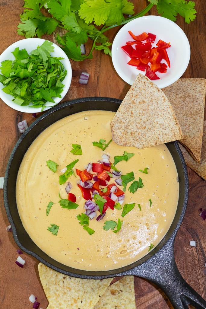 overhead shot of vegan queso in cast iron pan with chips and cilantro