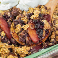 baking dish with blueberry peach crisp topped with vanilla ice cream