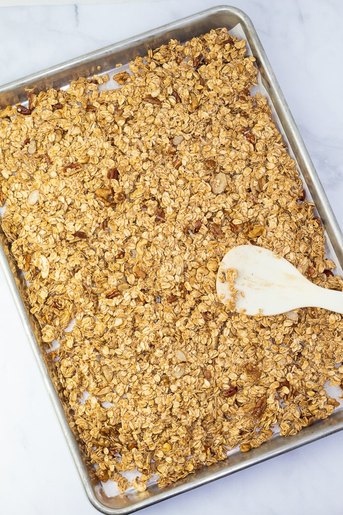 baking sheet with pressed raw gluten free granola and white spoon overhead shot