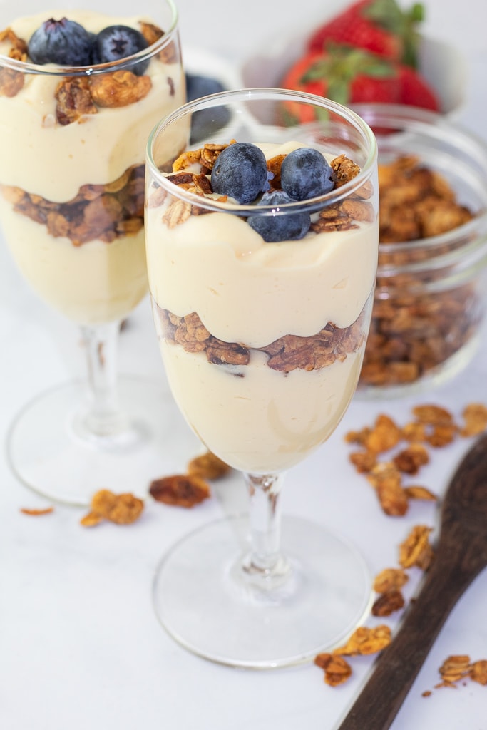 wine glasses filled with yogurt, granola, and blueberries