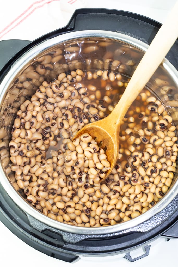 instant pot with cooked black eyed peas and wooden spoon in pot
