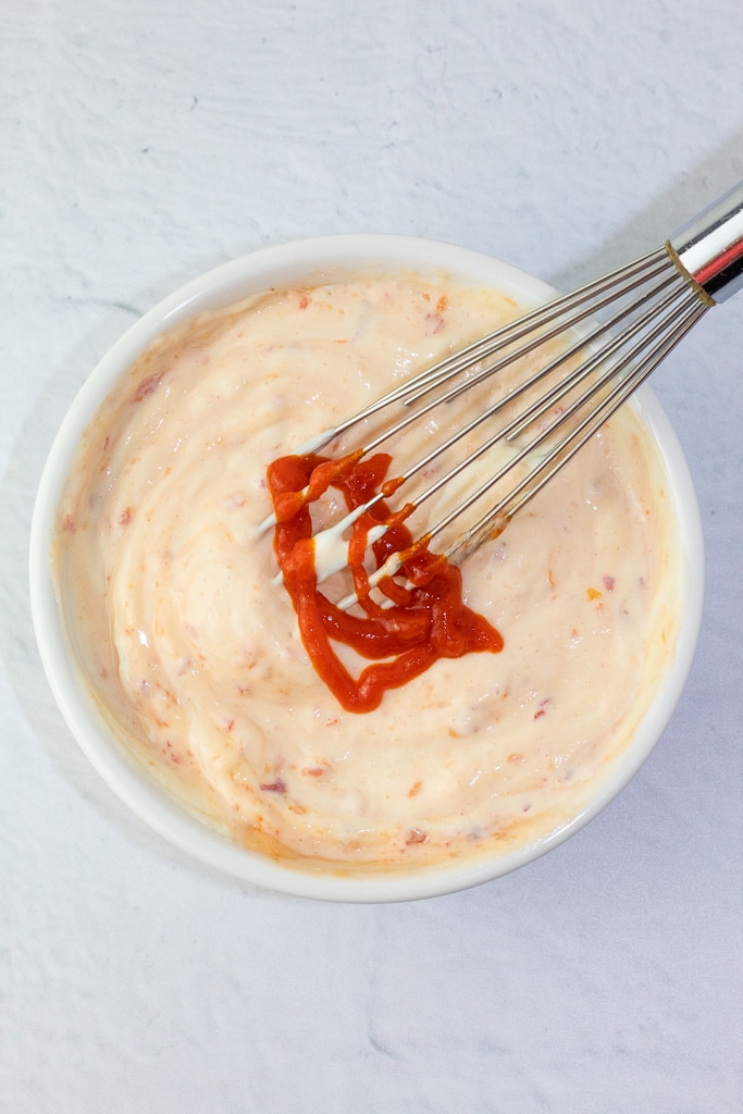 white bowl with vegan mayo and hot sauce with whisk