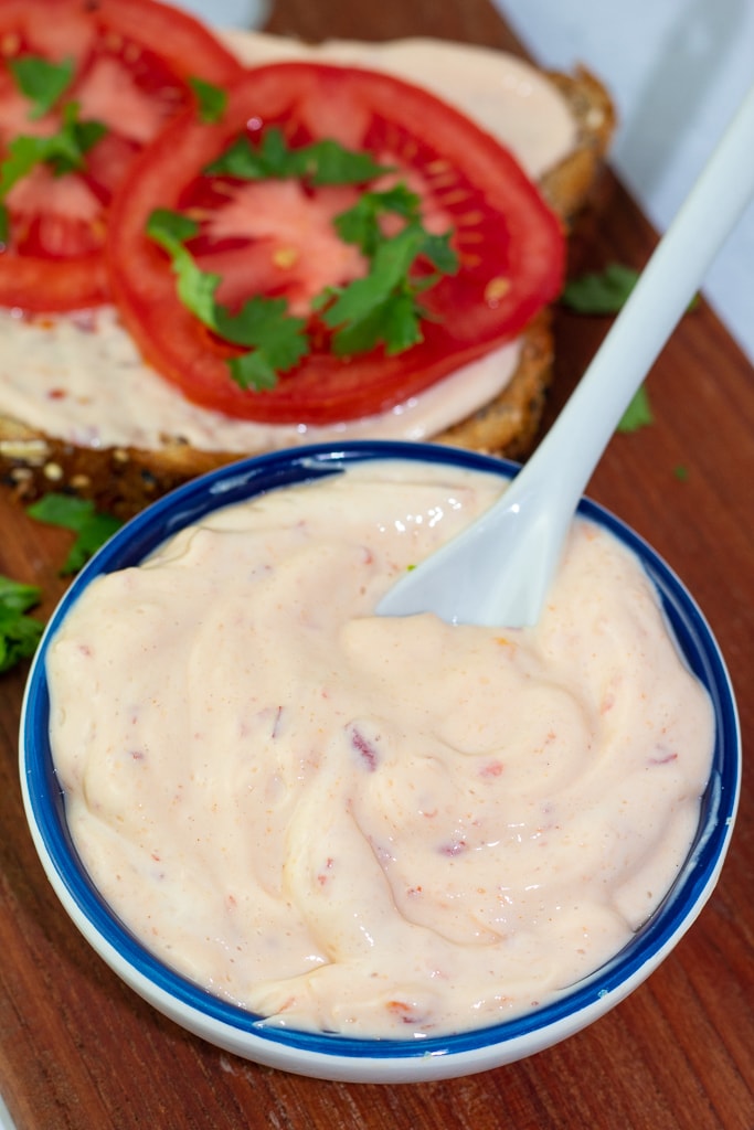 close of of blue bowl filled with vegan mayonnaise with hot sauce and tomatoes