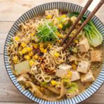 miso ramen with tofu and vegetables in a colorful bowl with chopsticks.