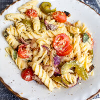 overhead shoto of vegan pasta primavera in country style plate with tomatoes