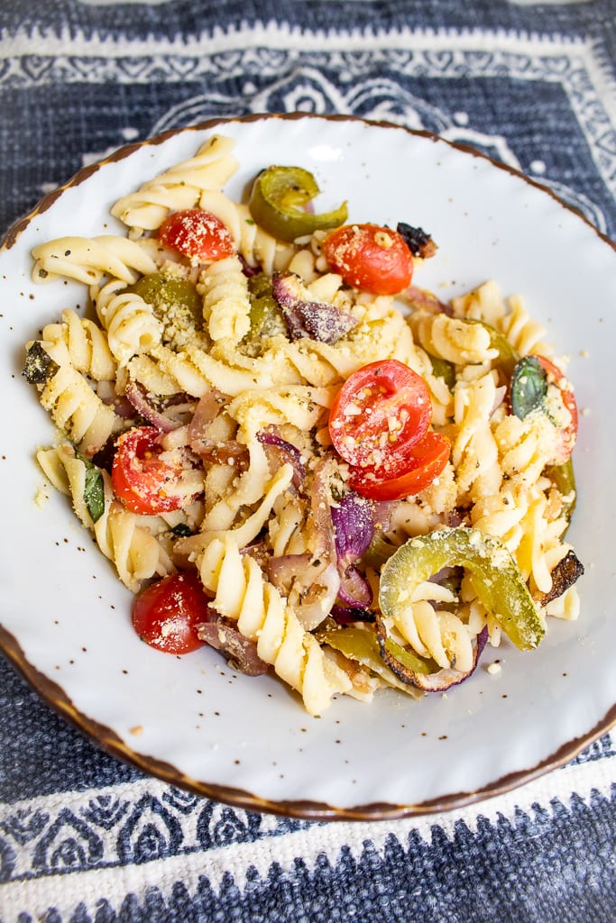 overhead shoto of vegan pasta primavera in country style plate with tomatoes