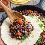 bean taco filling being spooned into a soft tortilla.