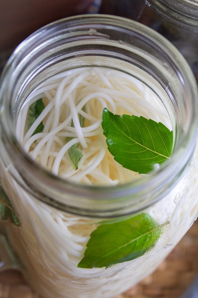 mason jar of somen noodles and water with mint leaves