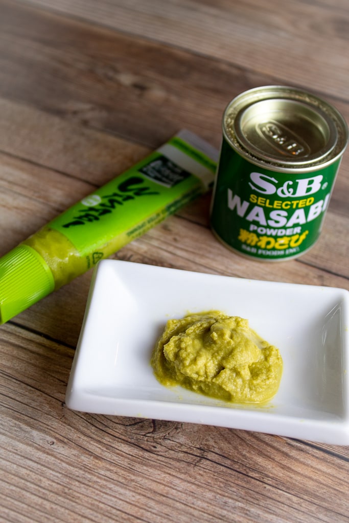 wasabi paste in white sauce dish with can of powder and paste beside