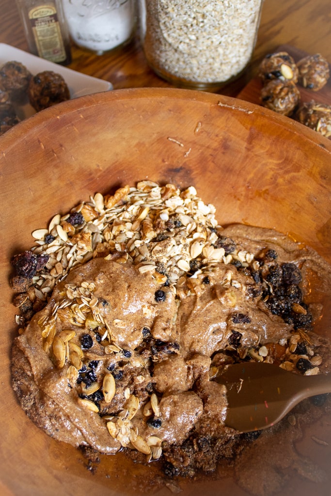 oat energy ball batter in wooden bowl being stirred with wooden spoon