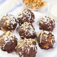 white plate with 7 chocolate balls sprinkled with shredded coconut and crushed walnuts