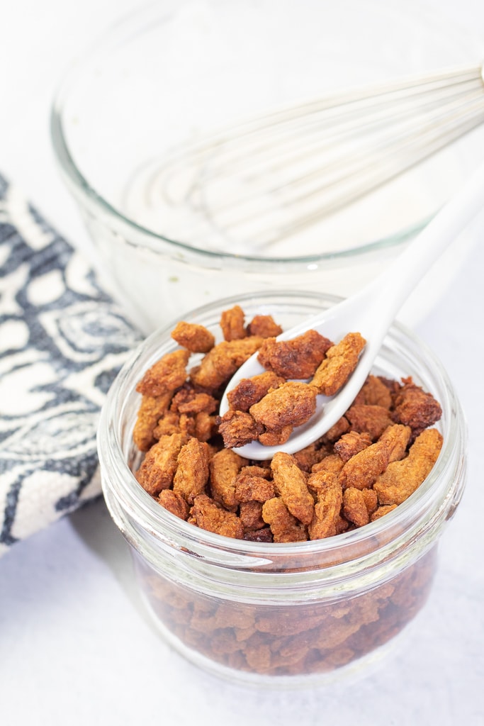glass mason jar with soy curl bacon bits with white spoon