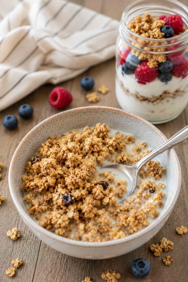 bowl of chewy peanut butter granola in a bowl with milk and a spoon.