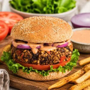 thick vegan black bean burger on a whole grain bun with lettuce, tomato, and chipotle sauce.