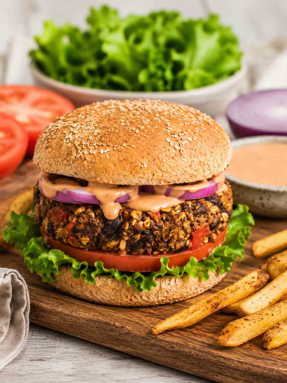thick vegan black bean burger on a whole grain bun with lettuce, tomato, and chipotle sauce.