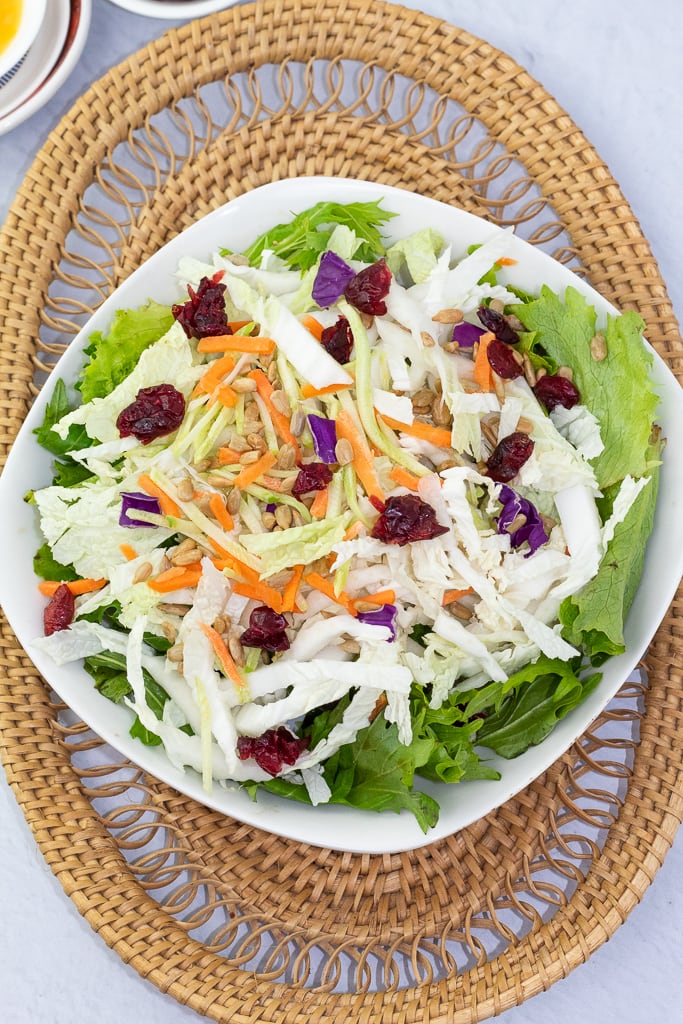 white plate full of napa cabbage salad on a basket place mat