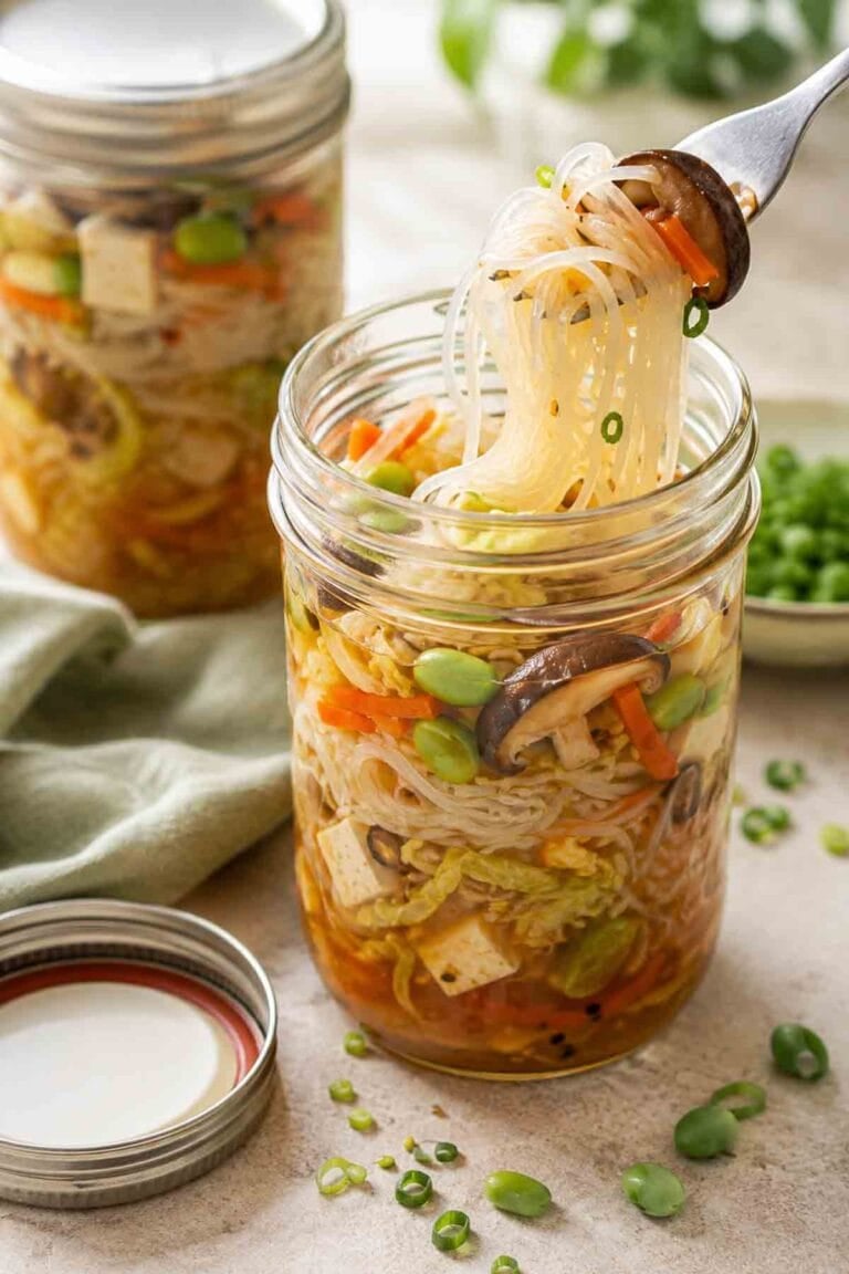 asian noodle mason jar soup with a fork pulling noodles out.