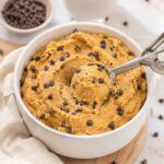 cookie dough in a white ceramic bowl with a small cookie scoop.