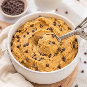 cookie dough in a white ceramic bowl with a small cookie scoop.