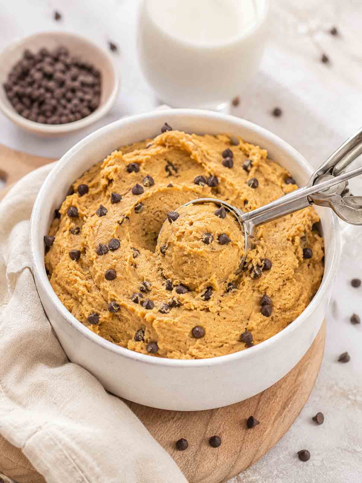 cookie dough in a white ceramic bowl with a small cookie scoop.