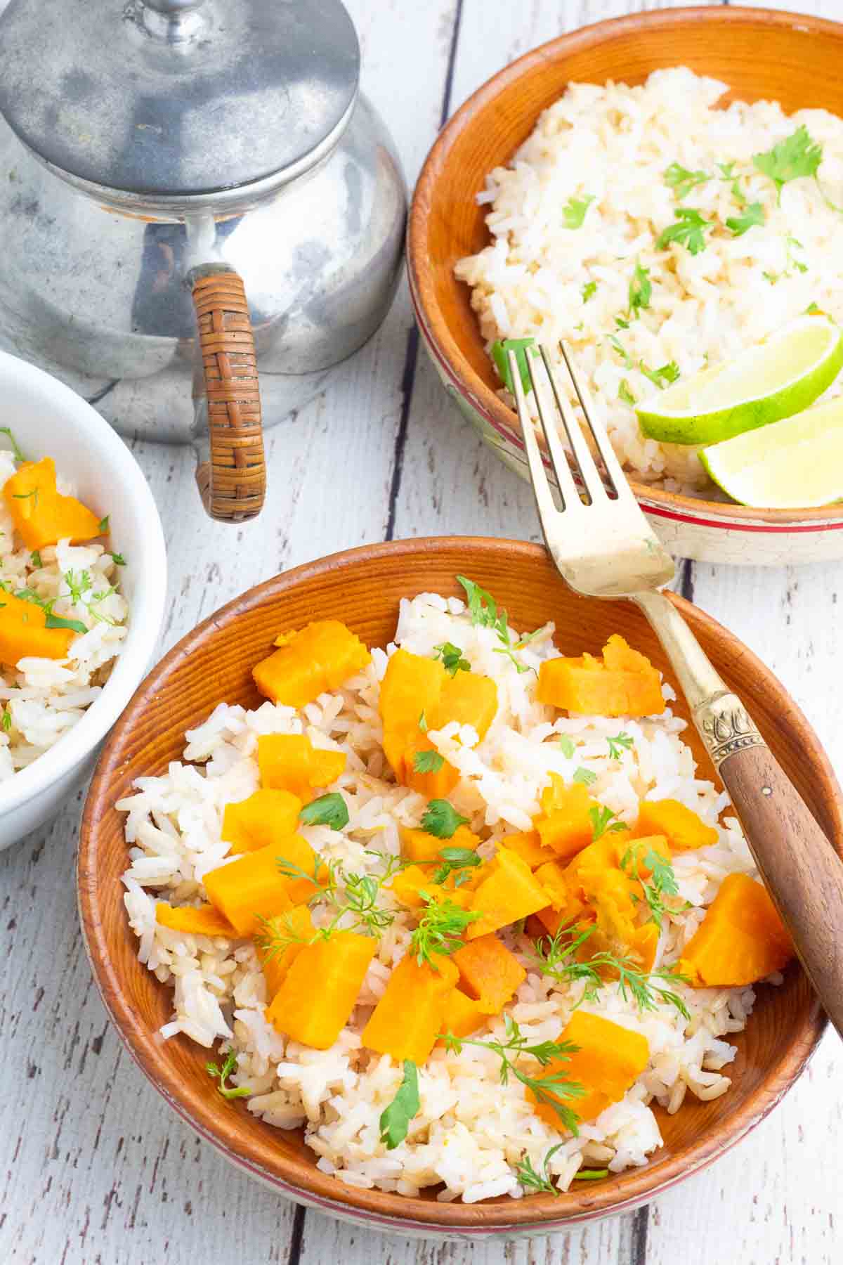 2 wooden bowls full of white rice, baked and cubed sweet potato, cilantro, and seasonings.