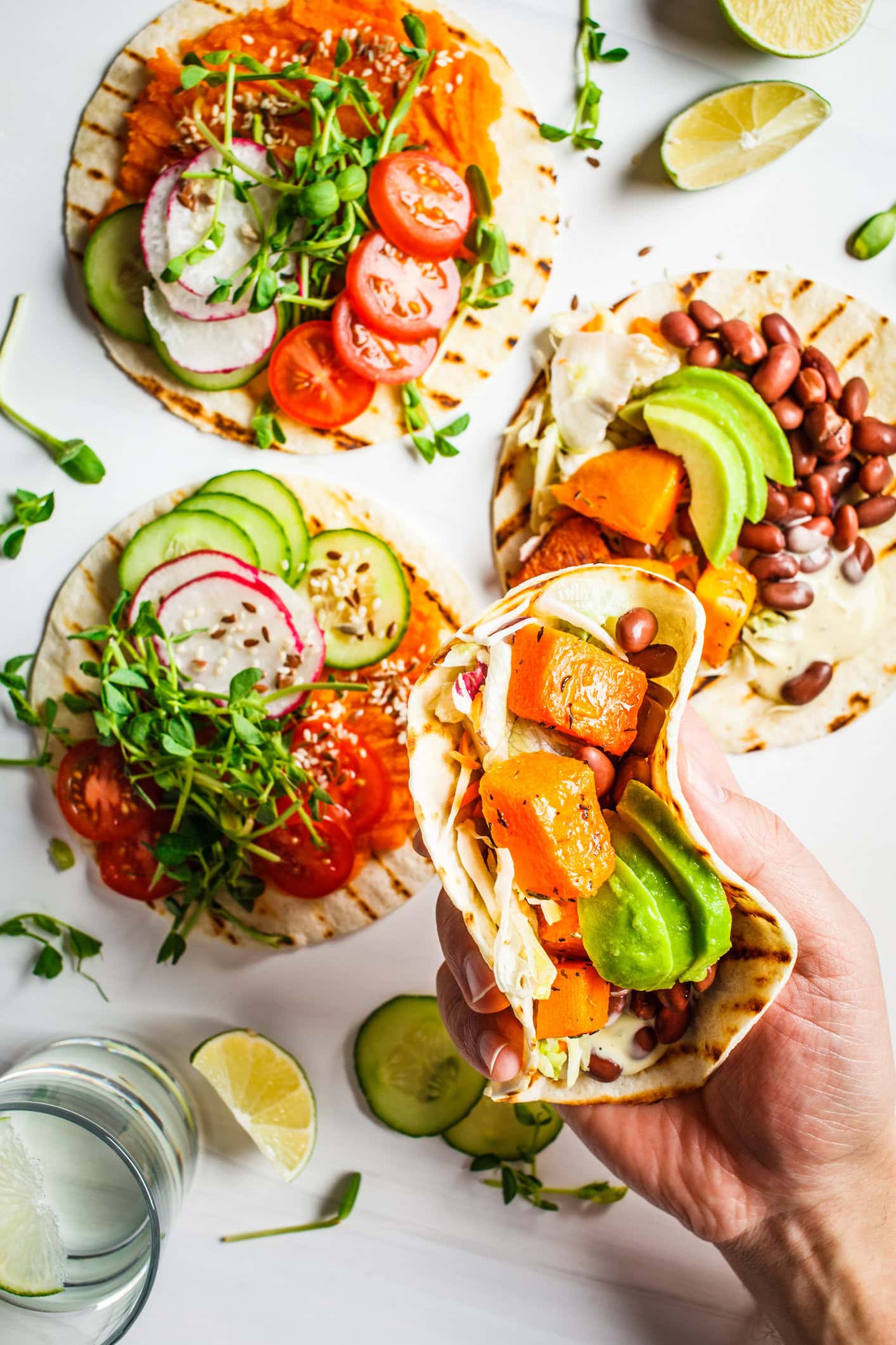 open vegan tortilla wraps with sweet potato, beans, avocado, tomatoes, pumpkin and seedlings on a white background.