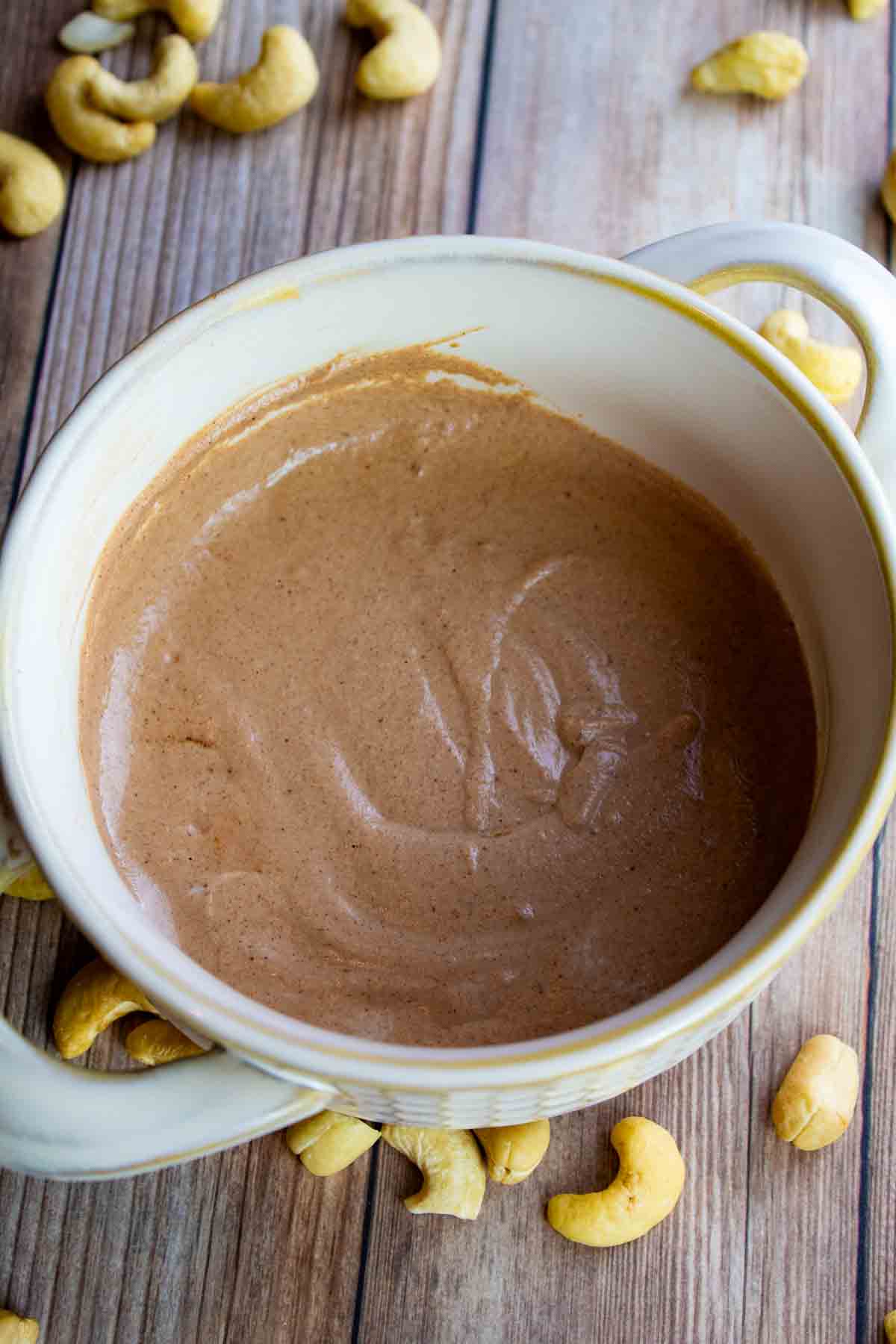 chocolate cashew cream in a white crock bowl with handles on each side.