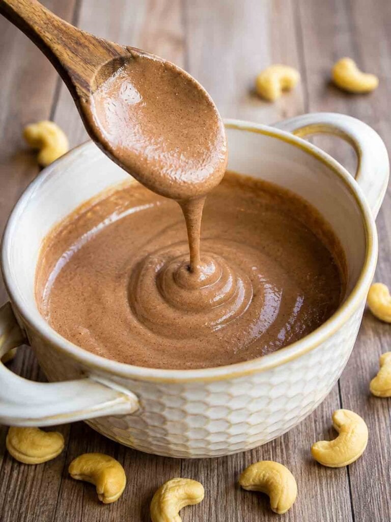 drizzle shot of chocolate cashew cream in a bowl with a wooden spoon.
