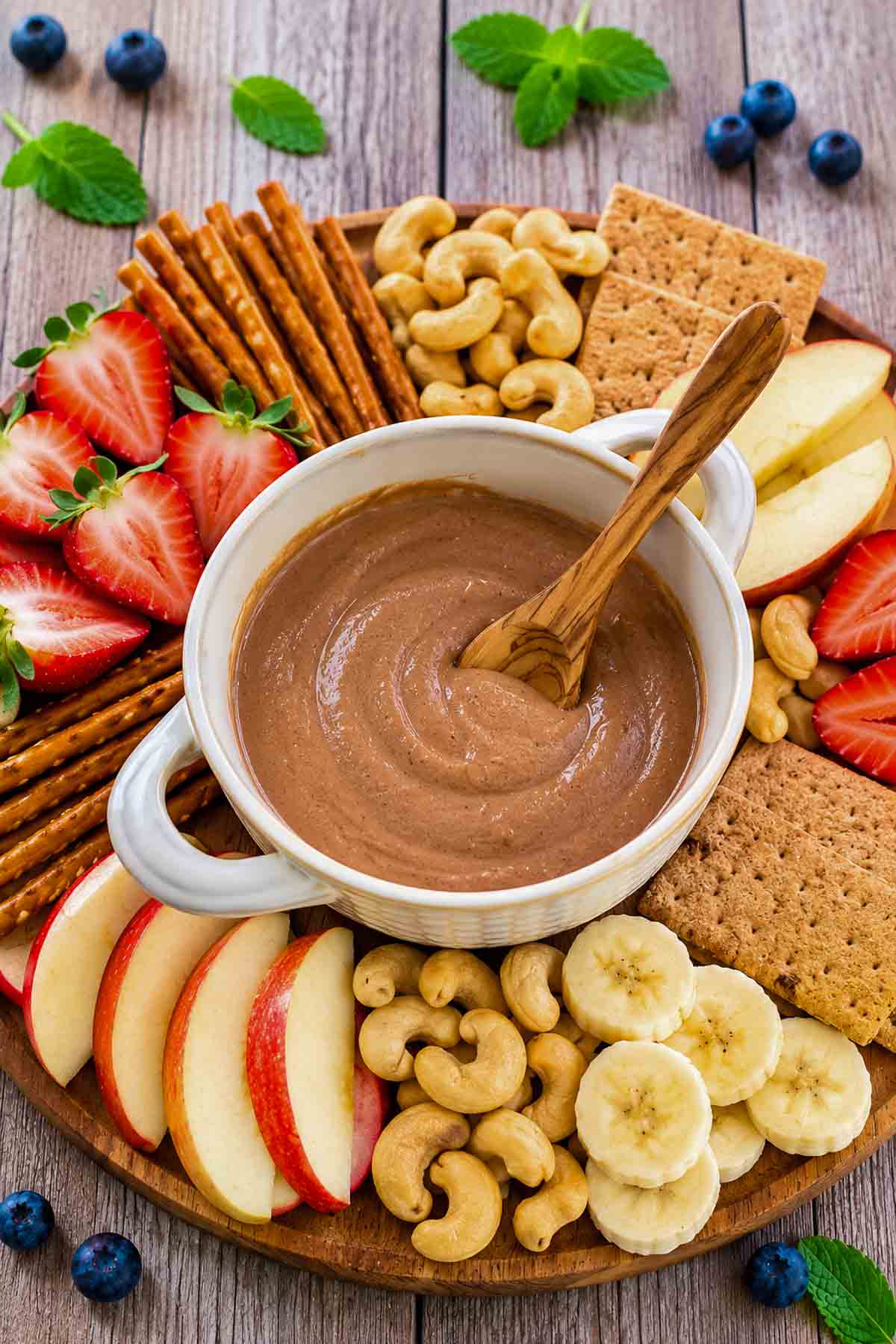 fruit charcuterie board with a bowl of chocolate cashew cream in the middle.
