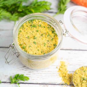 homemade vegetable boullion powder in a glass jar with lid on white wooden table.