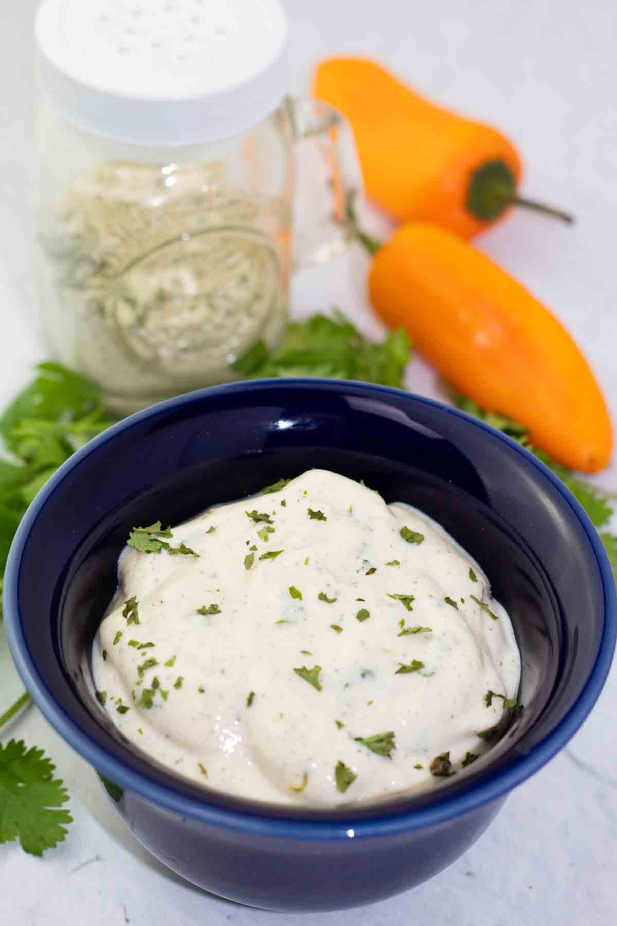 vegan ranch dip in a blue bowl with dairy-free ranch seasoning in bottle in the background.