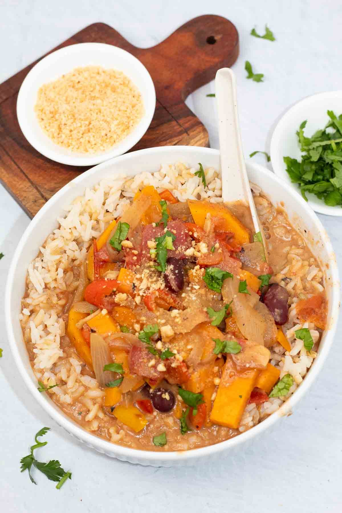 african sweet potato peanut stew in a white bowl with crushed peanuts and fresh cilantro.