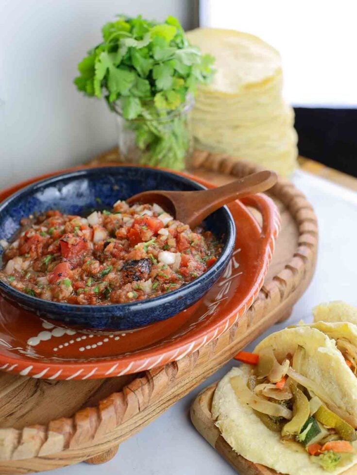 colorful bowl of chunky red salsa with soft corn tortillas filled with vegetables and salsa.