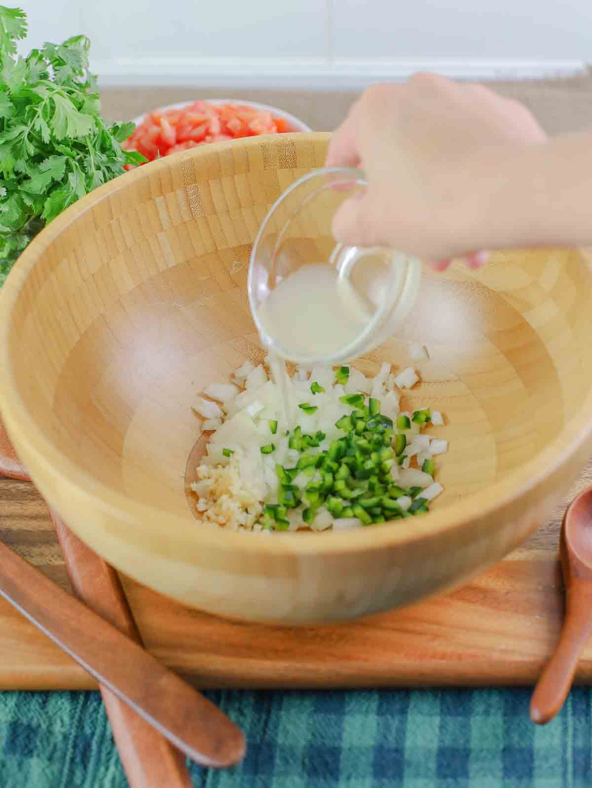 wooden bowl with diced jlapeno, chopped onion, and lime juice to make pico-de-gallo-.