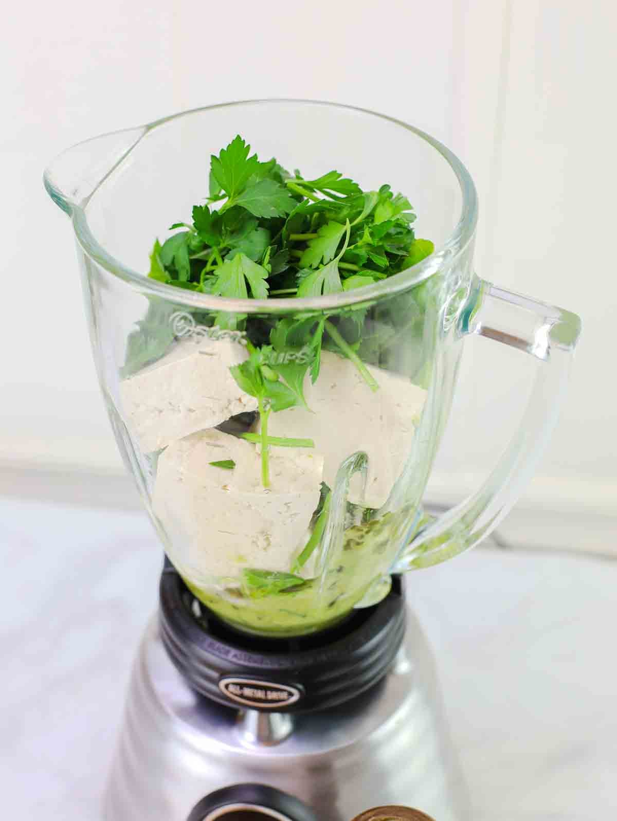 blender filled with ingredients for sauce for mexican green spaghetti ready to be blended.