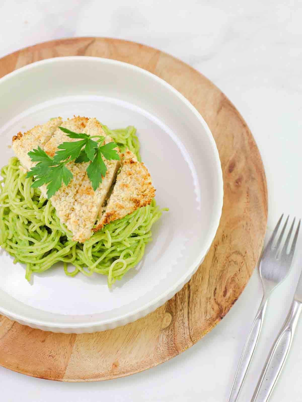 bowl of espagueti verde on a wooden cutting board.